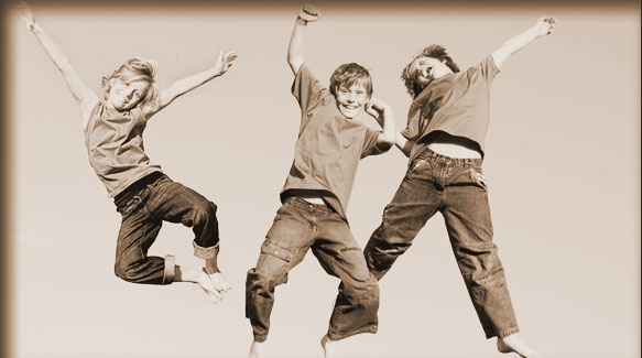 three smiling children jumping into the air